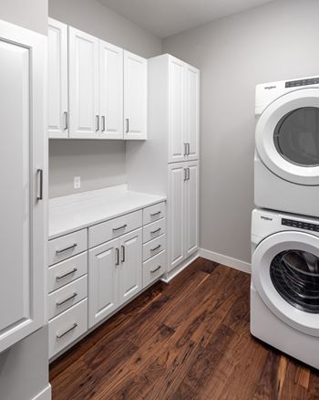 A laundry room with a washer and dryer and white cabinets